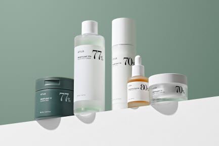 En upps&auml;ttning Anua hudv&aring;rdsprodukter p&aring; en vit yta framf&ouml;r en gr&ouml;n bakgrund. Produkten inkluderar ansiktskr&auml;m, serum, toner och en mask.